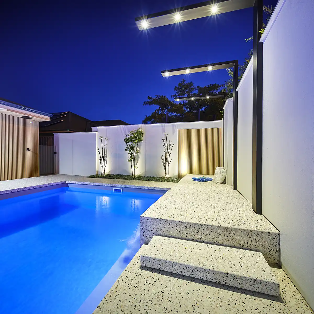 Cottesloe Series fibreglass pool with contemporary lighting and outdoor entertaining area at night.